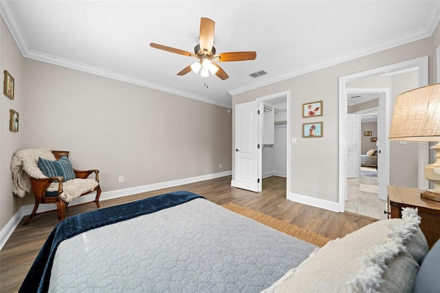 bedroom featuring visible vents, baseboards, wood finished floors, and crown molding