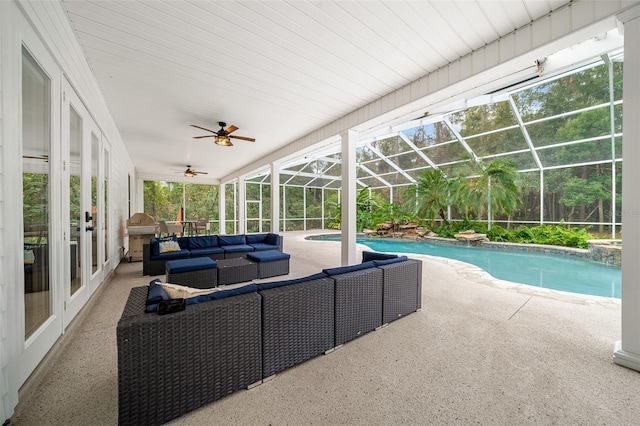 outdoor pool featuring glass enclosure, a ceiling fan, a patio area, and an outdoor hangout area