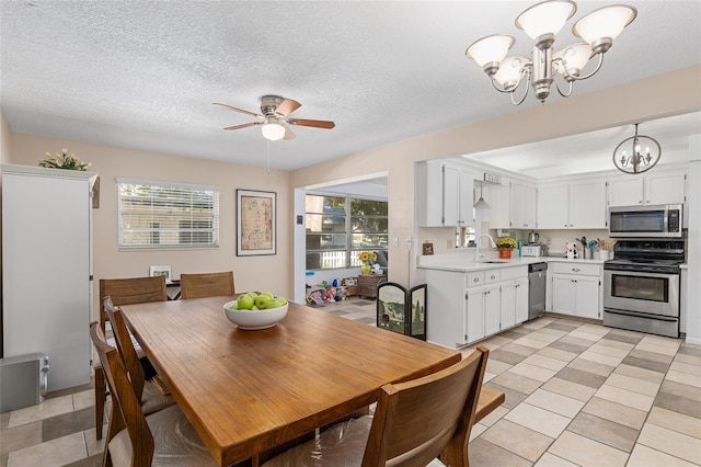 dining area featuring a textured ceiling, ceiling fan with notable chandelier, light tile patterned floors, and sink