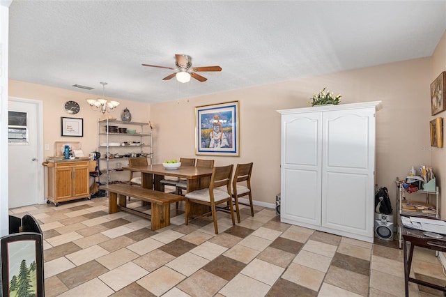 dining space with a textured ceiling and ceiling fan with notable chandelier