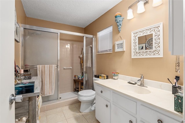 bathroom with tile patterned floors, toilet, a shower with door, and a textured ceiling