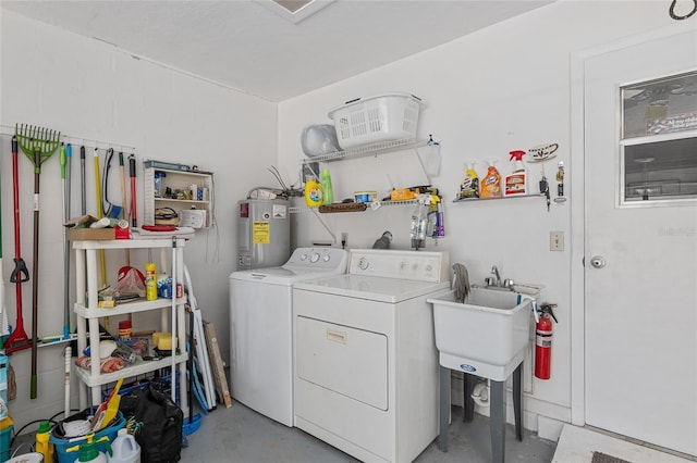 washroom featuring electric water heater, washer and clothes dryer, and sink