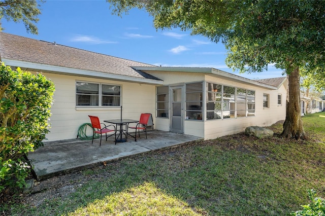 back of property with a yard, a patio, and a sunroom