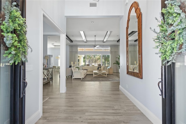 corridor with beam ceiling, coffered ceiling, and light wood-type flooring