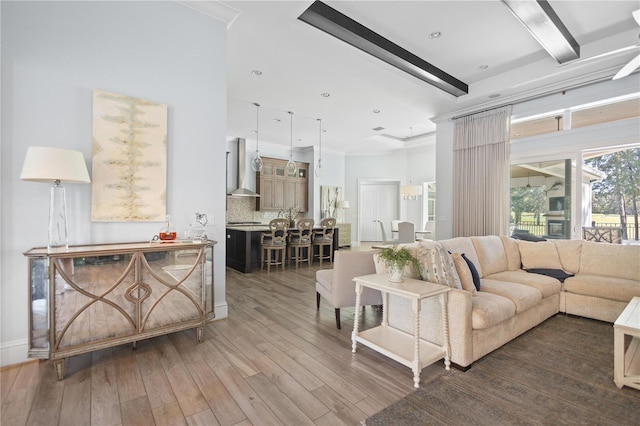 living room featuring beam ceiling, hardwood / wood-style flooring, and ornamental molding