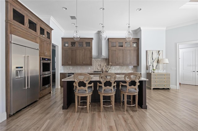 kitchen with hanging light fixtures, a kitchen island, stainless steel appliances, and light wood-type flooring