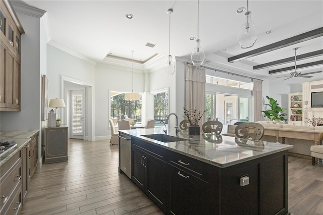 kitchen with dark hardwood / wood-style flooring, sink, light stone counters, and an island with sink