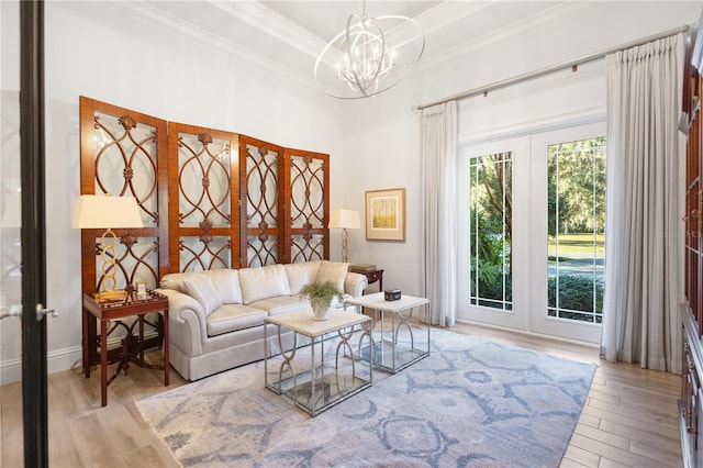 living room with a chandelier, french doors, light hardwood / wood-style floors, and crown molding