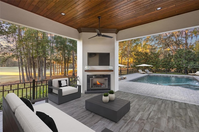 exterior space with an outdoor living space with a fireplace, ceiling fan, and a fenced in pool