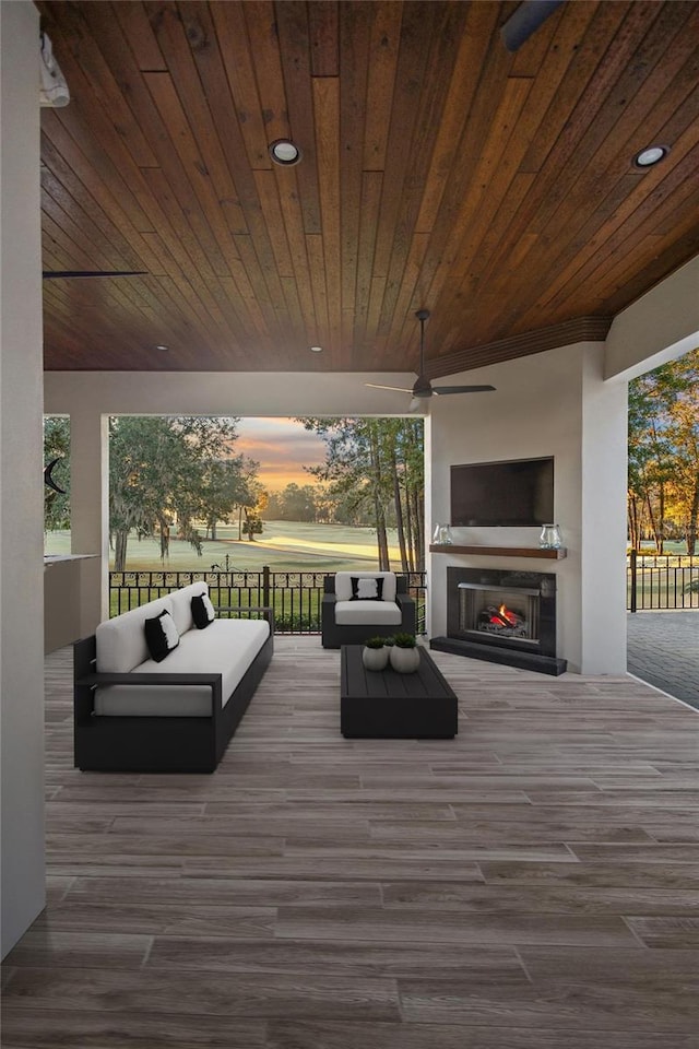 deck with an outdoor living space with a fireplace and ceiling fan