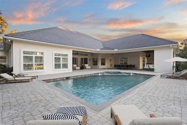 pool at dusk featuring a patio and an outdoor hangout area