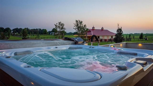 pool at dusk with a hot tub