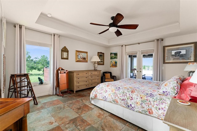 bedroom with a raised ceiling, access to exterior, and multiple windows