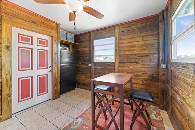 kitchen featuring black fridge, a healthy amount of sunlight, and wood walls