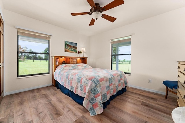 bedroom featuring light wood-type flooring, multiple windows, and ceiling fan