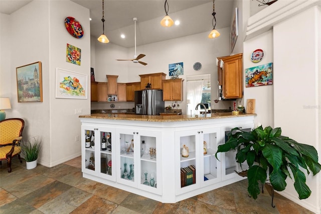 kitchen featuring stainless steel refrigerator with ice dispenser, ceiling fan, hanging light fixtures, and a high ceiling