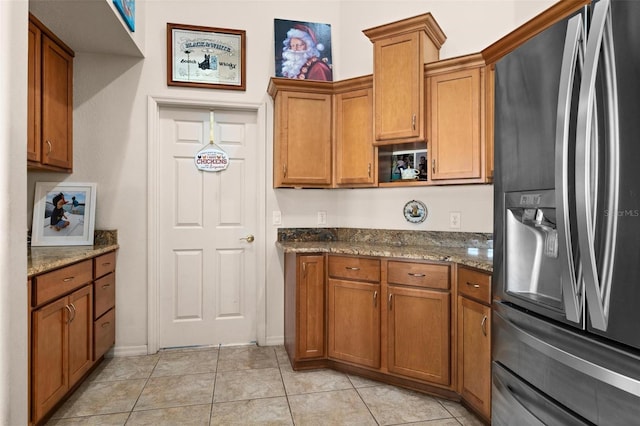 kitchen with stone counters, stainless steel refrigerator with ice dispenser, and light tile patterned flooring