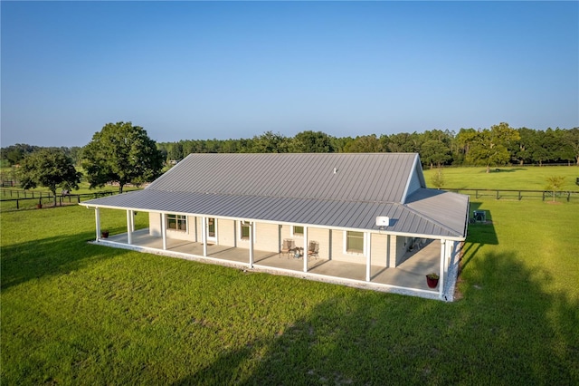 back of house featuring a yard, a patio, and a rural view