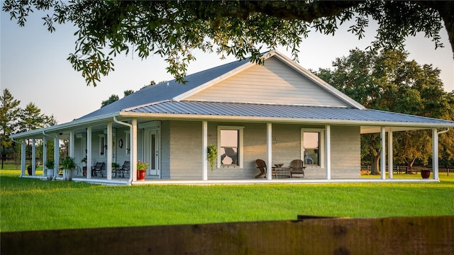 back of property featuring a porch, a yard, and metal roof