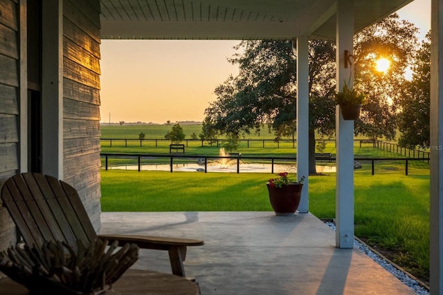 exterior space featuring a rural view, a patio area, and a lawn