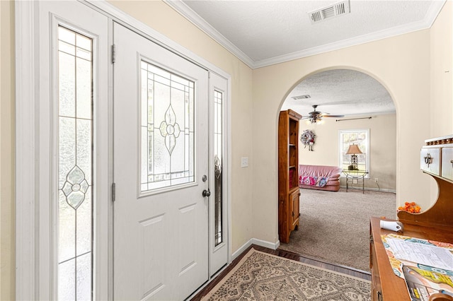 carpeted entryway with ceiling fan, a textured ceiling, and ornamental molding