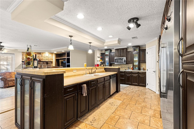 kitchen with sink, stainless steel appliances, decorative light fixtures, a kitchen island with sink, and dark brown cabinets