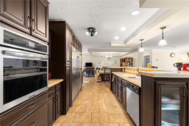 kitchen featuring dark brown cabinets, stainless steel appliances, and hanging light fixtures