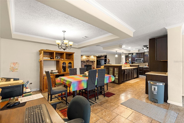 dining area with a textured ceiling, a tray ceiling, and ornamental molding