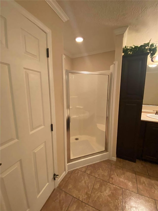 bathroom featuring tile patterned floors, walk in shower, a textured ceiling, vanity, and crown molding