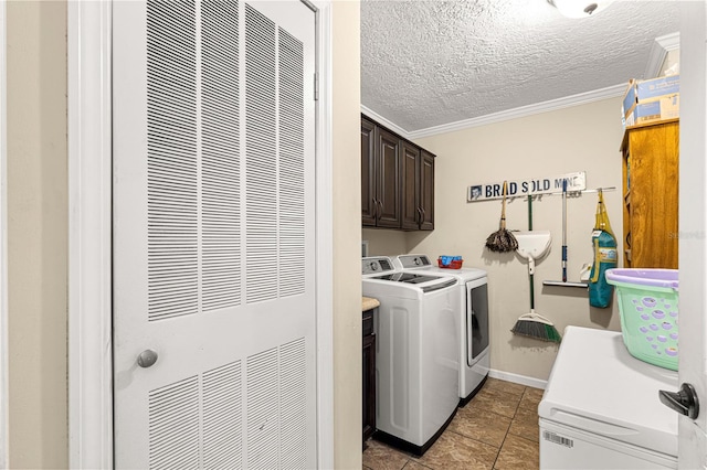 laundry room featuring cabinets, washing machine and dryer, crown molding, a textured ceiling, and light tile patterned floors