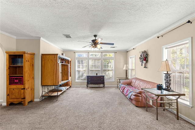 carpeted living room featuring ceiling fan, a healthy amount of sunlight, and ornamental molding