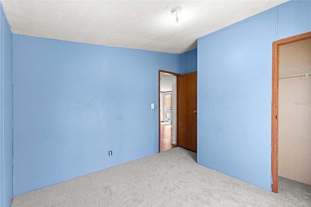 unfurnished bedroom with a textured ceiling, light colored carpet, and a closet