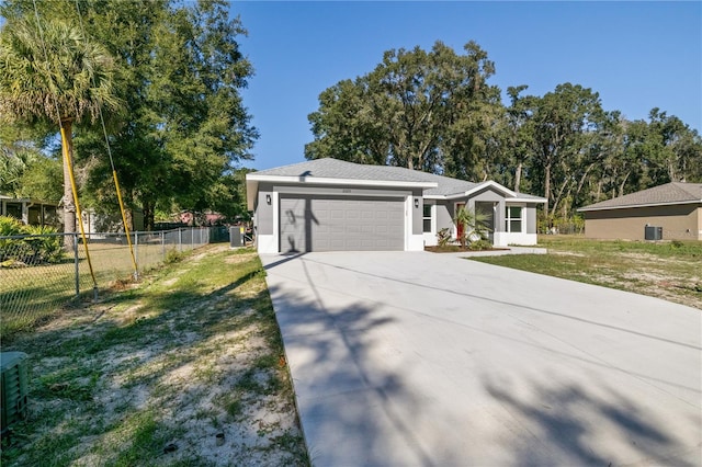 ranch-style house with a garage, central air condition unit, and a front yard