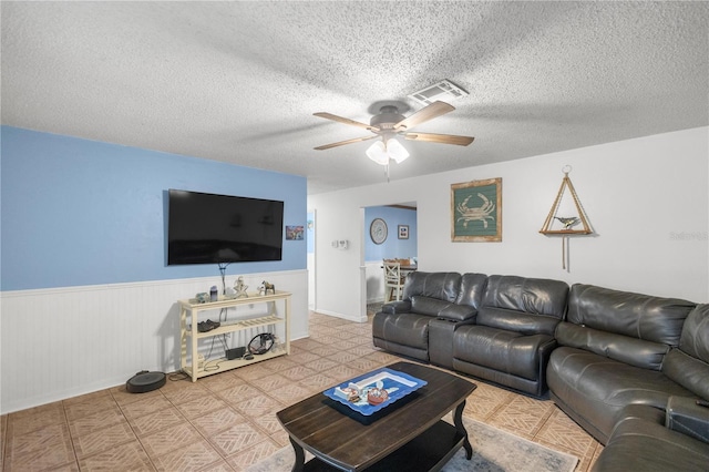 living room featuring ceiling fan and a textured ceiling