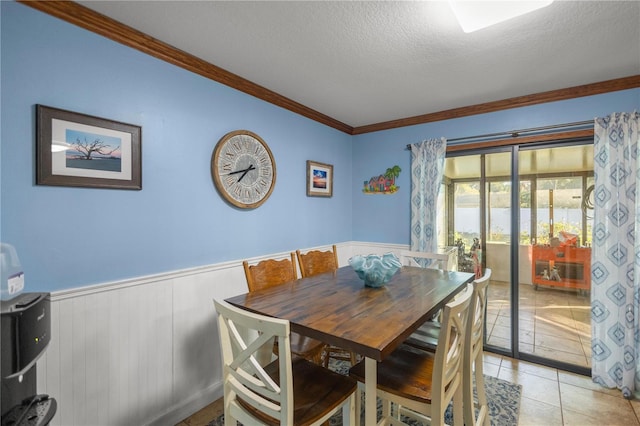 dining space with ornamental molding, light tile patterned floors, and a textured ceiling