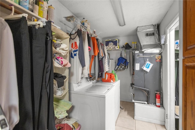 clothes washing area with separate washer and dryer, light tile patterned floors, and a textured ceiling