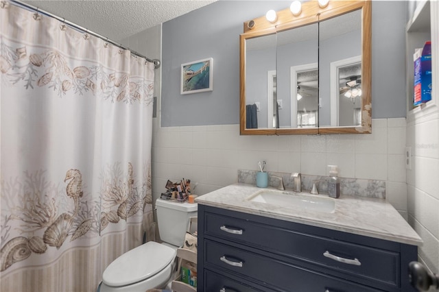 bathroom with toilet, a textured ceiling, tile walls, vanity, and ceiling fan