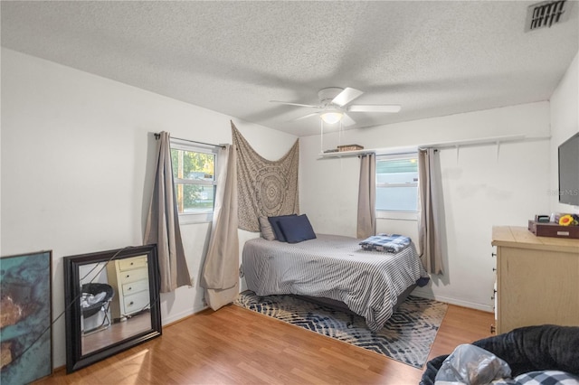 bedroom featuring ceiling fan, a textured ceiling, and light wood-type flooring