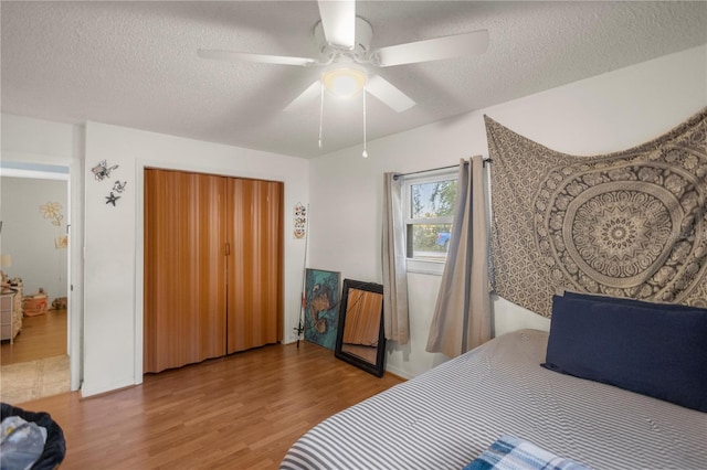 bedroom featuring hardwood / wood-style floors, a closet, a textured ceiling, and ceiling fan