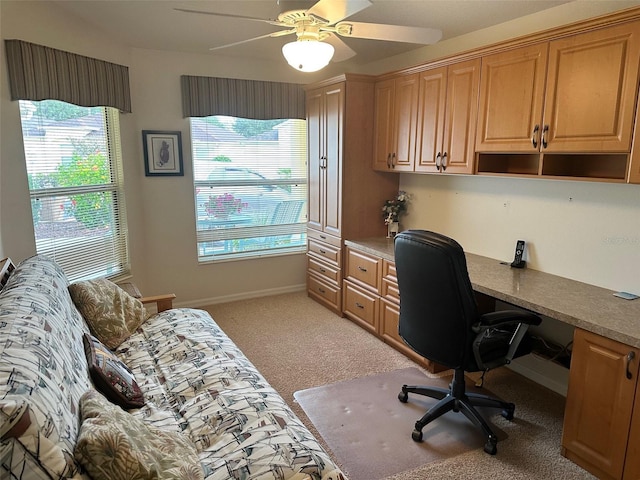 carpeted office with ceiling fan, a healthy amount of sunlight, and built in desk