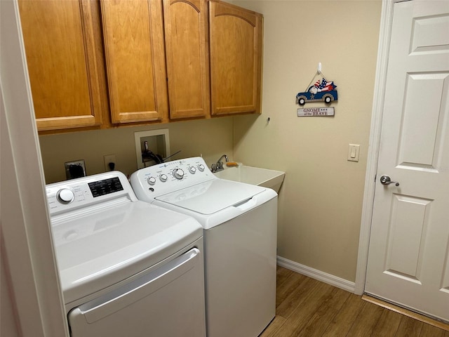 clothes washing area featuring hardwood / wood-style flooring, cabinets, independent washer and dryer, and sink