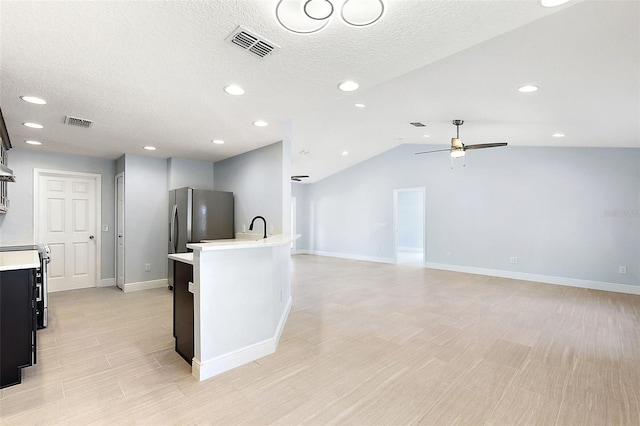 kitchen with ceiling fan, stainless steel fridge, light wood-type flooring, and lofted ceiling