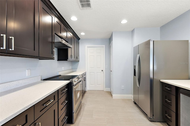 kitchen featuring light stone counters, dark brown cabinets, stainless steel appliances, and a textured ceiling