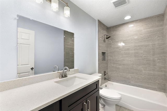 full bathroom featuring vanity, tiled shower / bath combo, a textured ceiling, and toilet