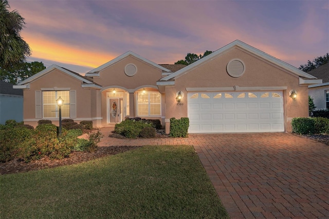 ranch-style home with a garage and a yard