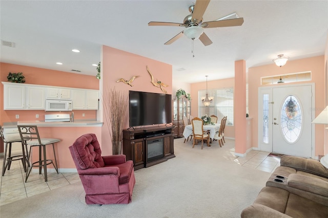 tiled living room featuring a fireplace and ceiling fan with notable chandelier