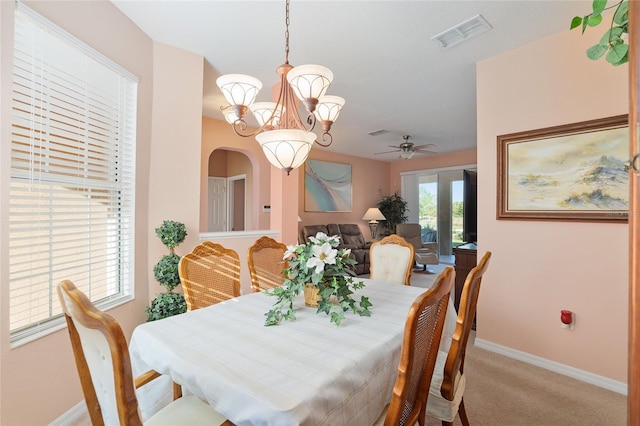 carpeted dining space featuring ceiling fan with notable chandelier and french doors