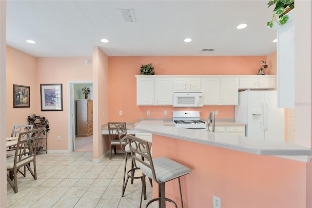 kitchen featuring kitchen peninsula, a kitchen breakfast bar, white appliances, light tile patterned floors, and white cabinets