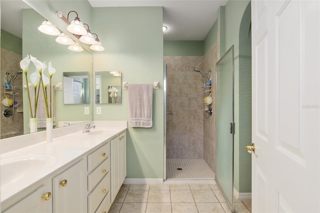 bathroom with tiled shower, a textured ceiling, vanity, and tile patterned floors