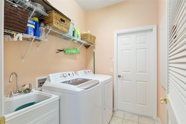 clothes washing area with sink, light tile patterned floors, and washer and dryer